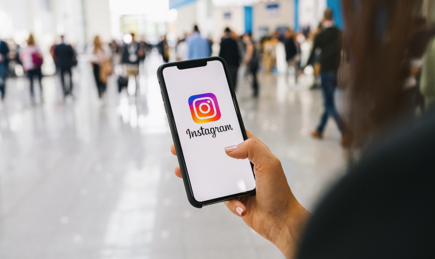 Eine Strategie und klar definierte Ziele sind wichtig, um soziale Medien optimal zu nutzen Person mit Instagram auf dem Handy während eines Messebesuchs
