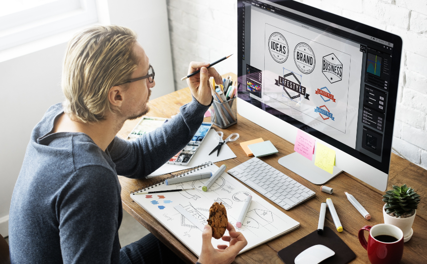 Dem Logo oder Firmenmottos kommen bei der Layoutgestaltung natürlich eine besondere Bedeutung zu Mann am Computer, der sein Werbe-Display-Layout gestaltet
